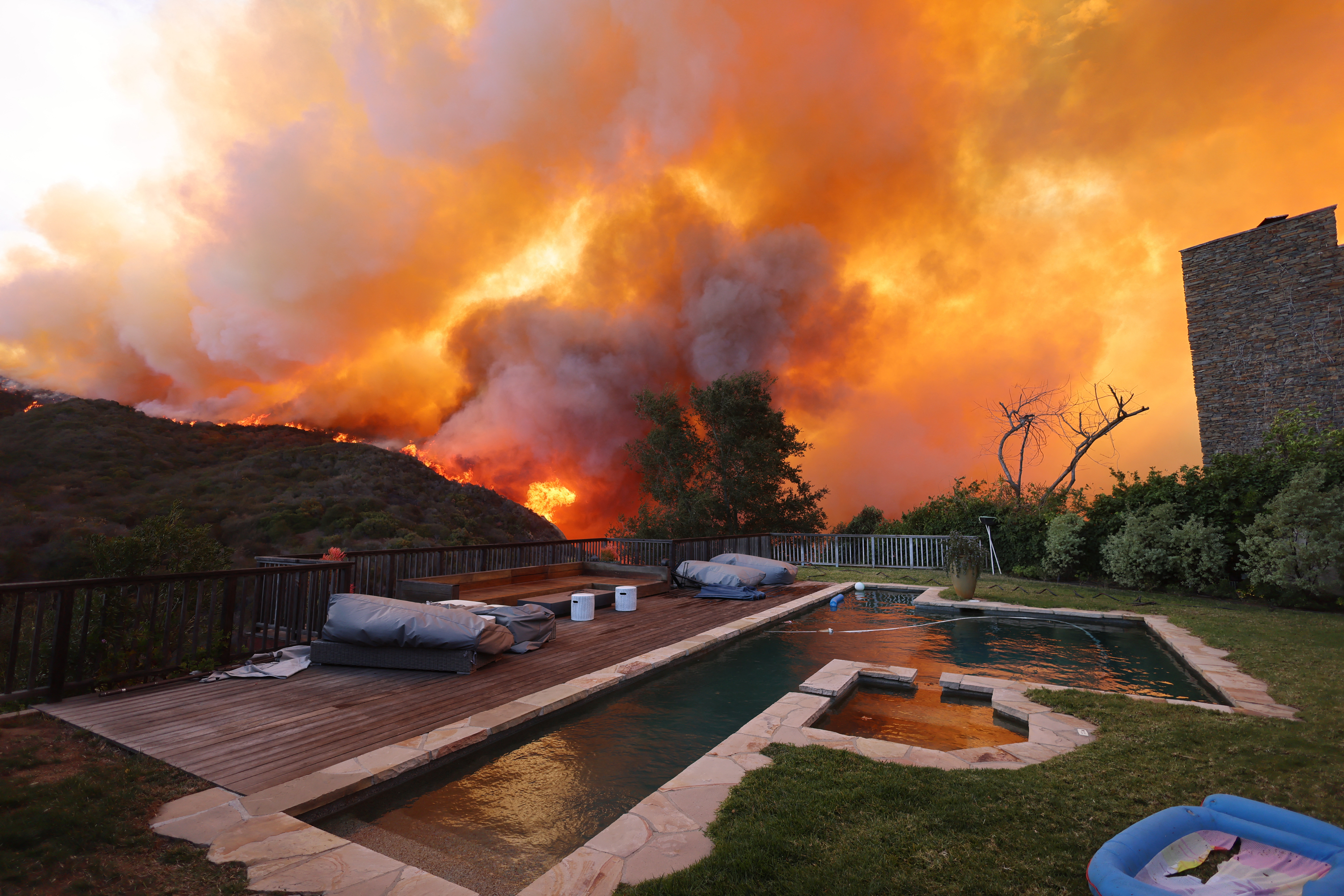 wildfire in california with a swimming pool in foreground and smoke in background