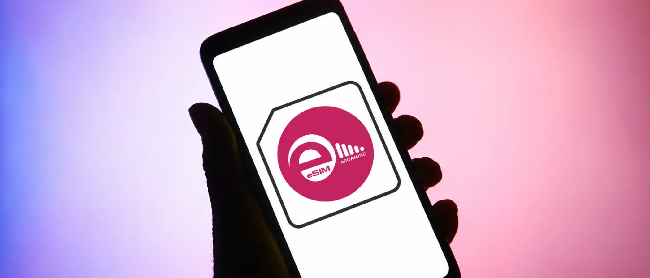 The eRoaming eSIM logo on a phone screen held by a silhouetted hand