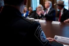 A CBP officer listens to Trump