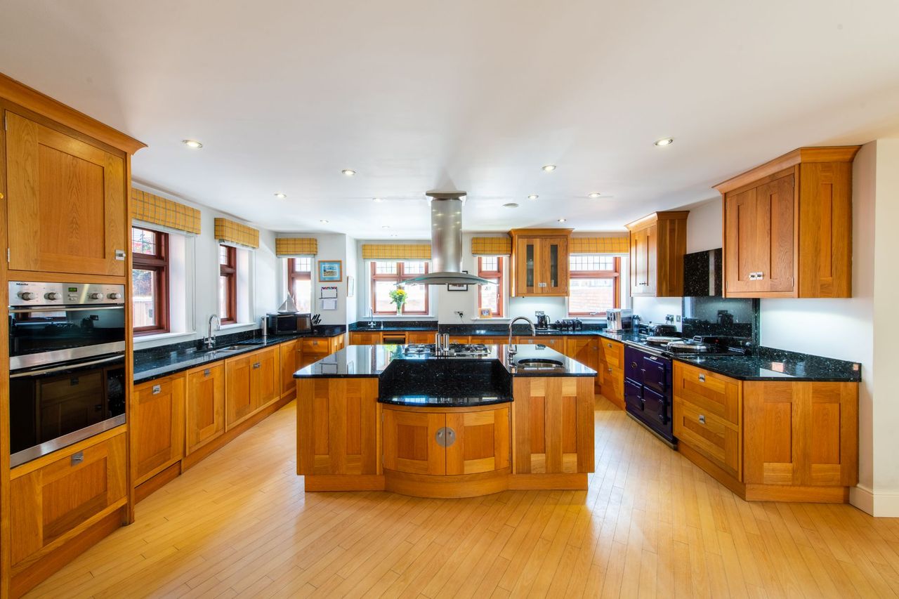 A wooden floored kitchen with a kitchen island and wooden cabinets