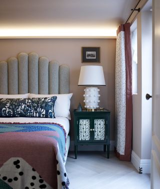 Pink bedroom with grey headboard and green side table