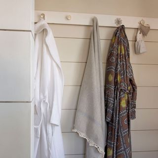 white wall hooks with dressing gowns and towels