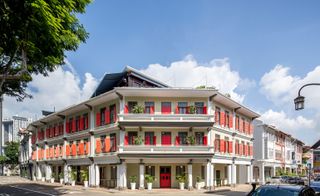 Exterior of white hotel with brightly painted window shutters