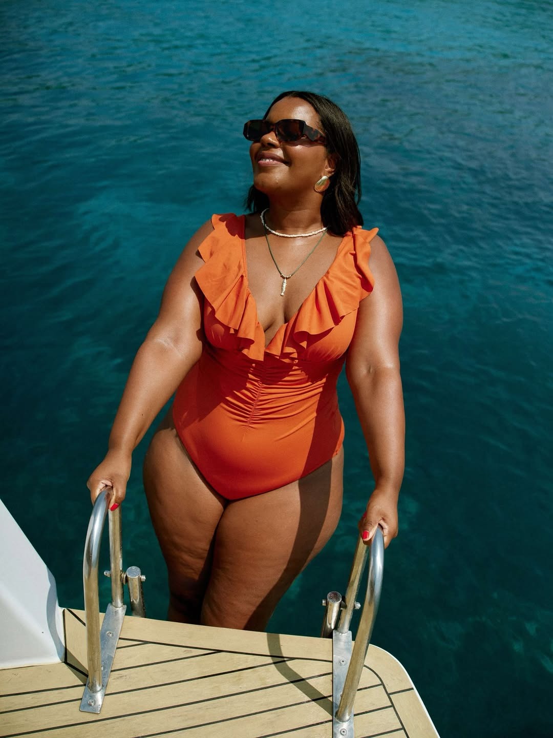 Woman in orange swimsuit and fish necklace