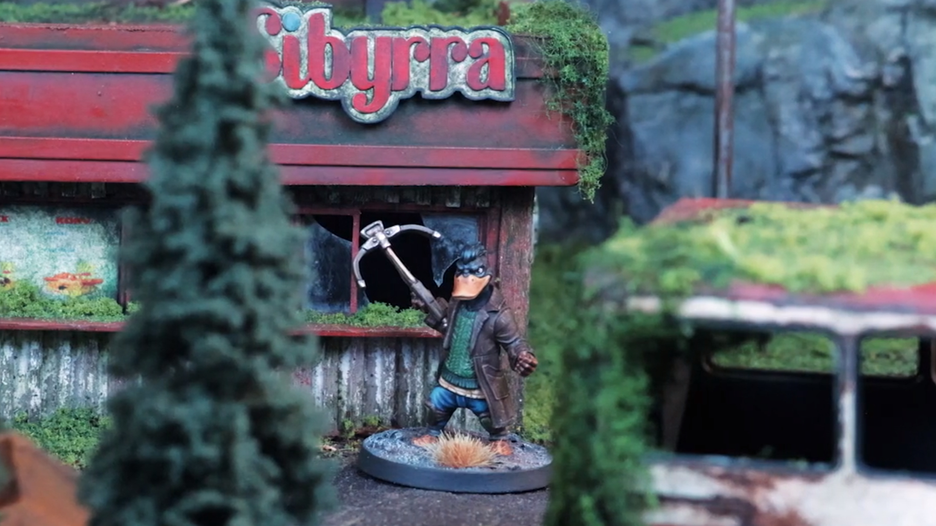 A closeup shot of a Zone Wars miniature near a broken shop, partially obscured by trees