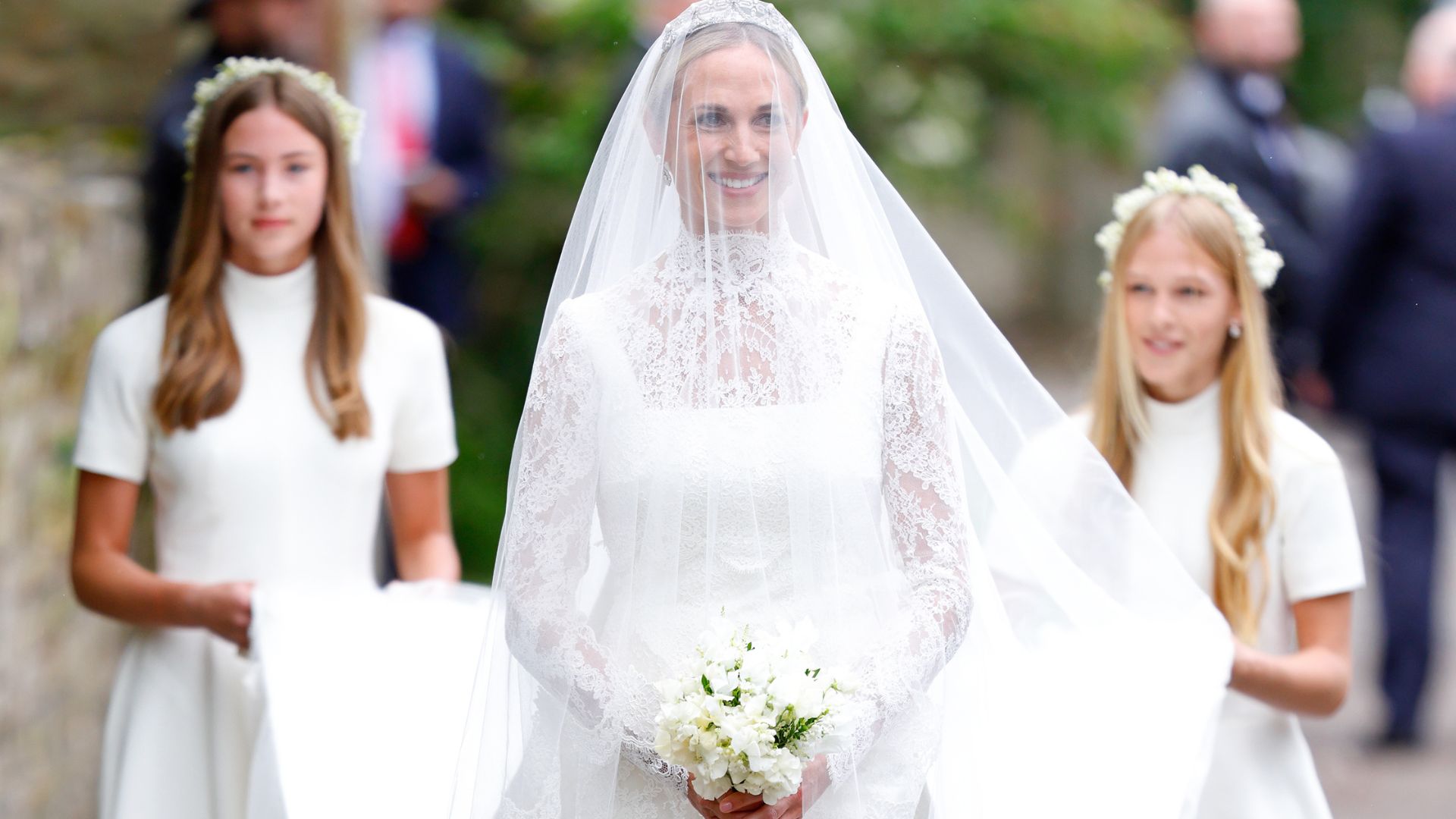 Harriet Sperling, accompanied by her bridesmaids - daughter Georgina Sperling (L) and step-daughter Isla Phillips (R), arrives at All Saints' Church for her wedding