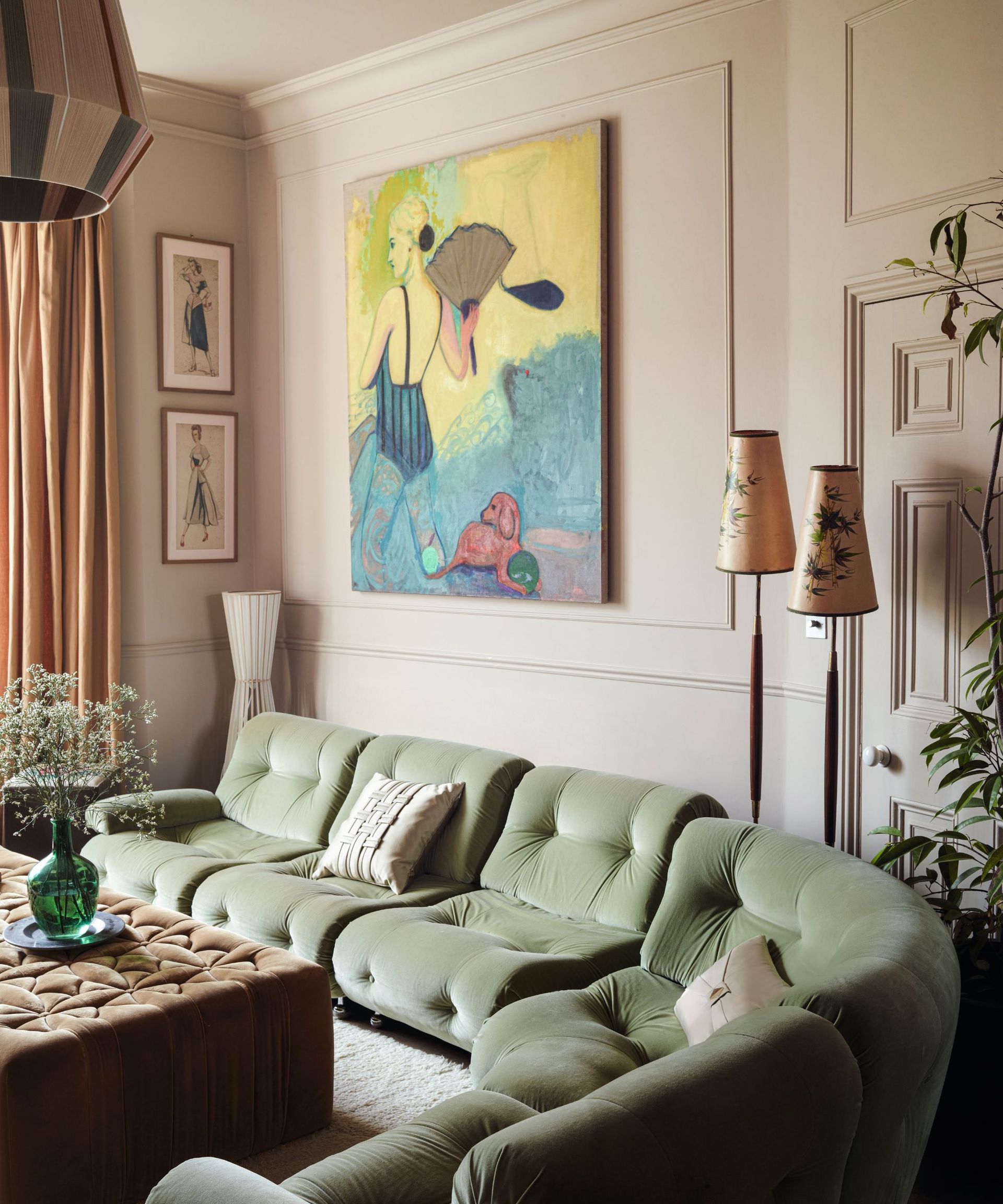 Pale pink panelled living room with velvet green sofa, large painting and velvet ottoman