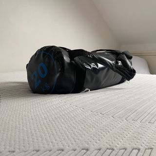 mattress with no bedding in a white room with a 20kg weight on top