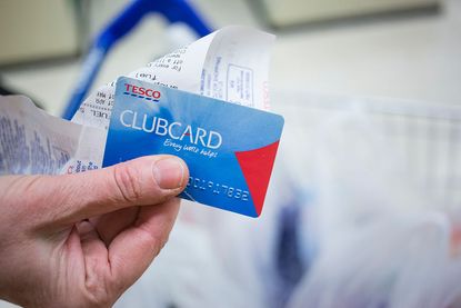 Customer holding a Tesco clubcard and a receipt 