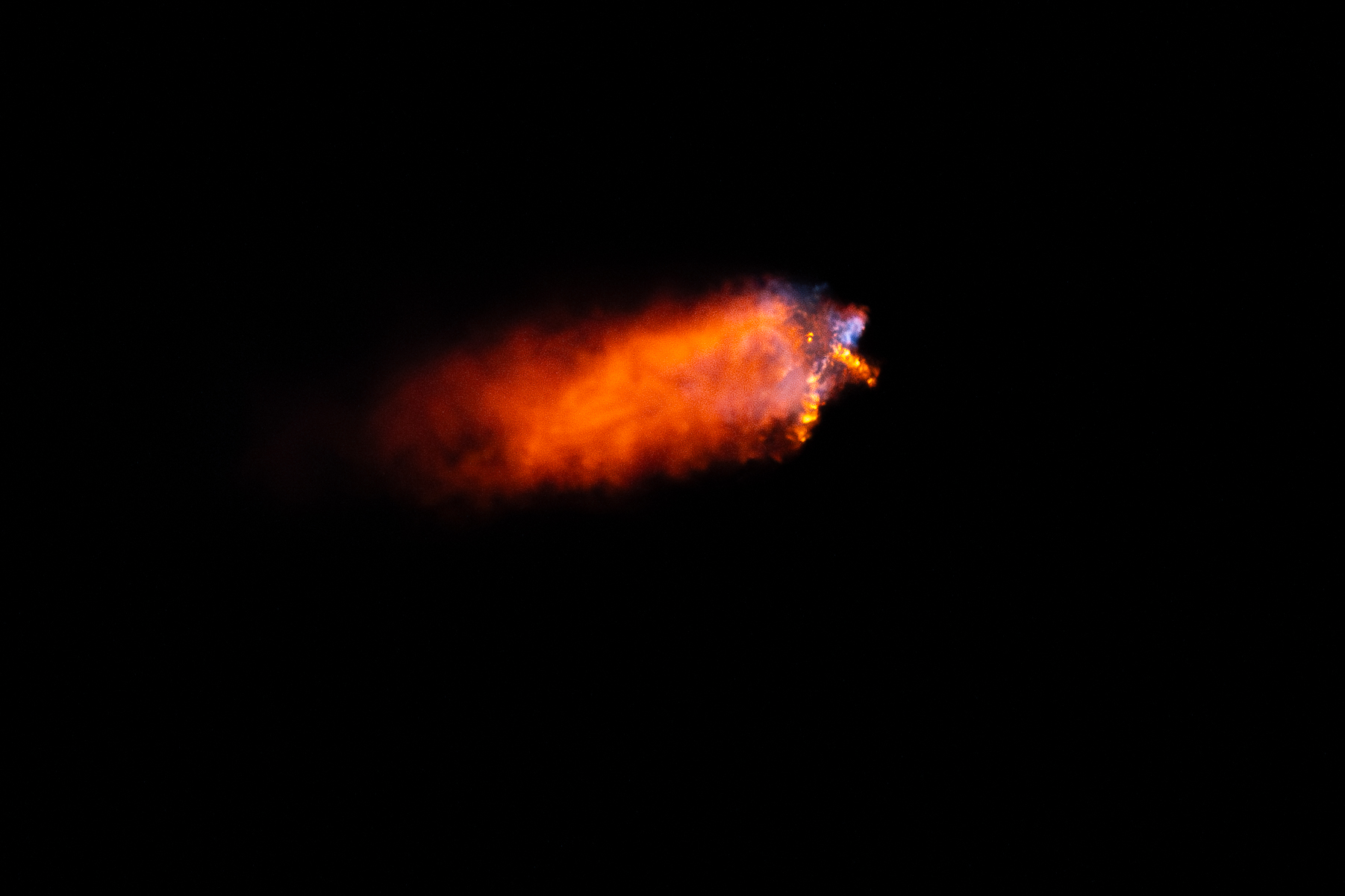 Un cohete se lanza por la noche y deja una brillante columna de fuego a su paso.
