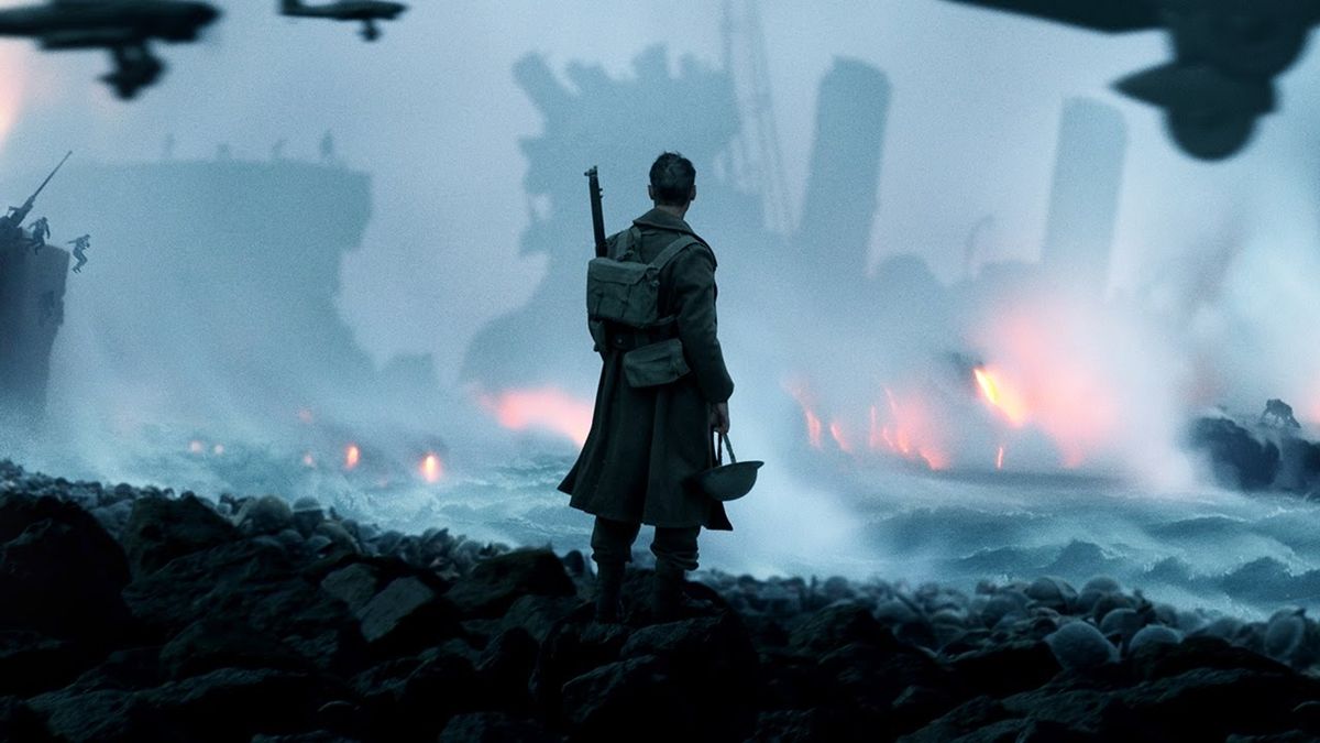 A still from the movie Dunkirk in which one of the soldier characters looks out onto the beach amidst fighting and destruction.