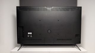 Amazon Fire TV Omni Mini-LED 65-inch TV on white shelving unit showing rear of TV