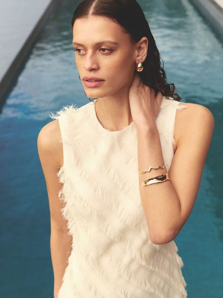 Woman posing in white top next to pool