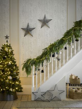entrance hall with Christmas tree, garland on the stairs, metal stairs, rug, bench with baskets of presents