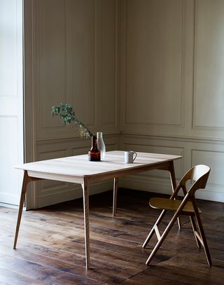 A photo of a wooden table with four slim table legs and a wooden desk chair.