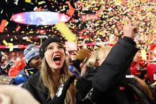 Taylor Swift at the AFC Championships wearing a louis vuitton jacket and matching knit beanie