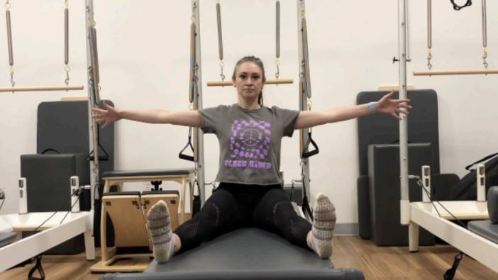 Woman on a Reformer Pilates machine demonstrating an exercise