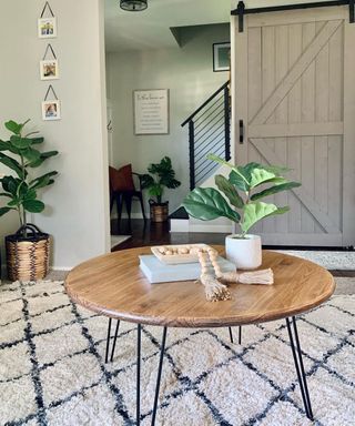 A round DIY wood and wire coffee table in living room with Berber rug and sliding barn door
