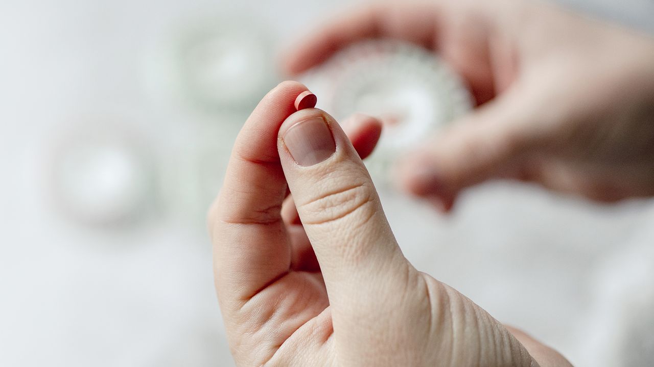 Close-up of a woman&#039;s hands holding HRT pills