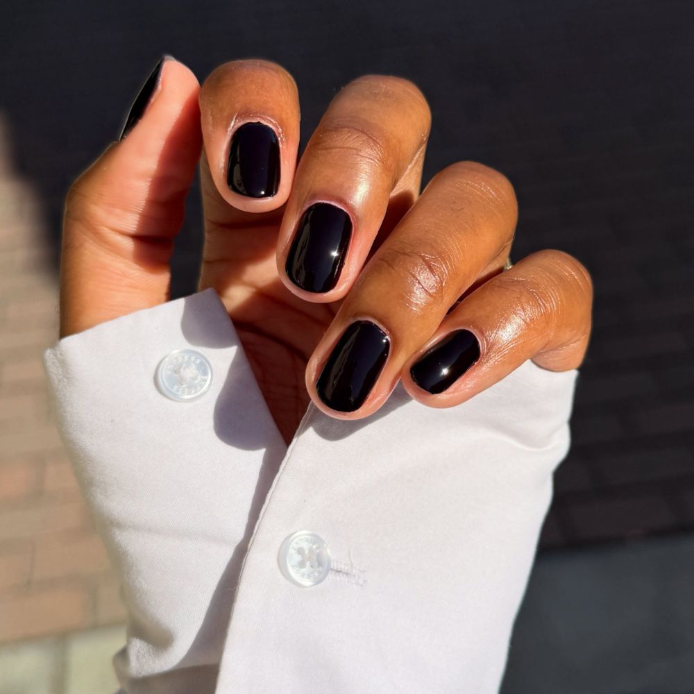 A close-up picture of a short, glossy black manicure