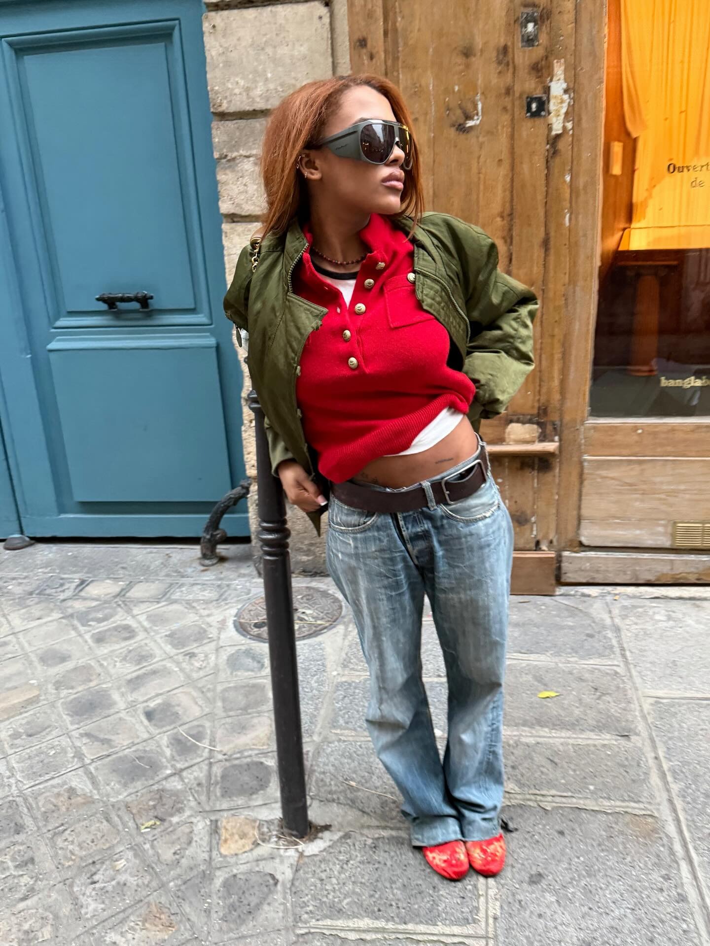 fashion person mv.tiangue wears the embellished mesh mule fashion trend summer 2026. She wears blue jeans a red polo, green jacket and red and gold embellished mules.