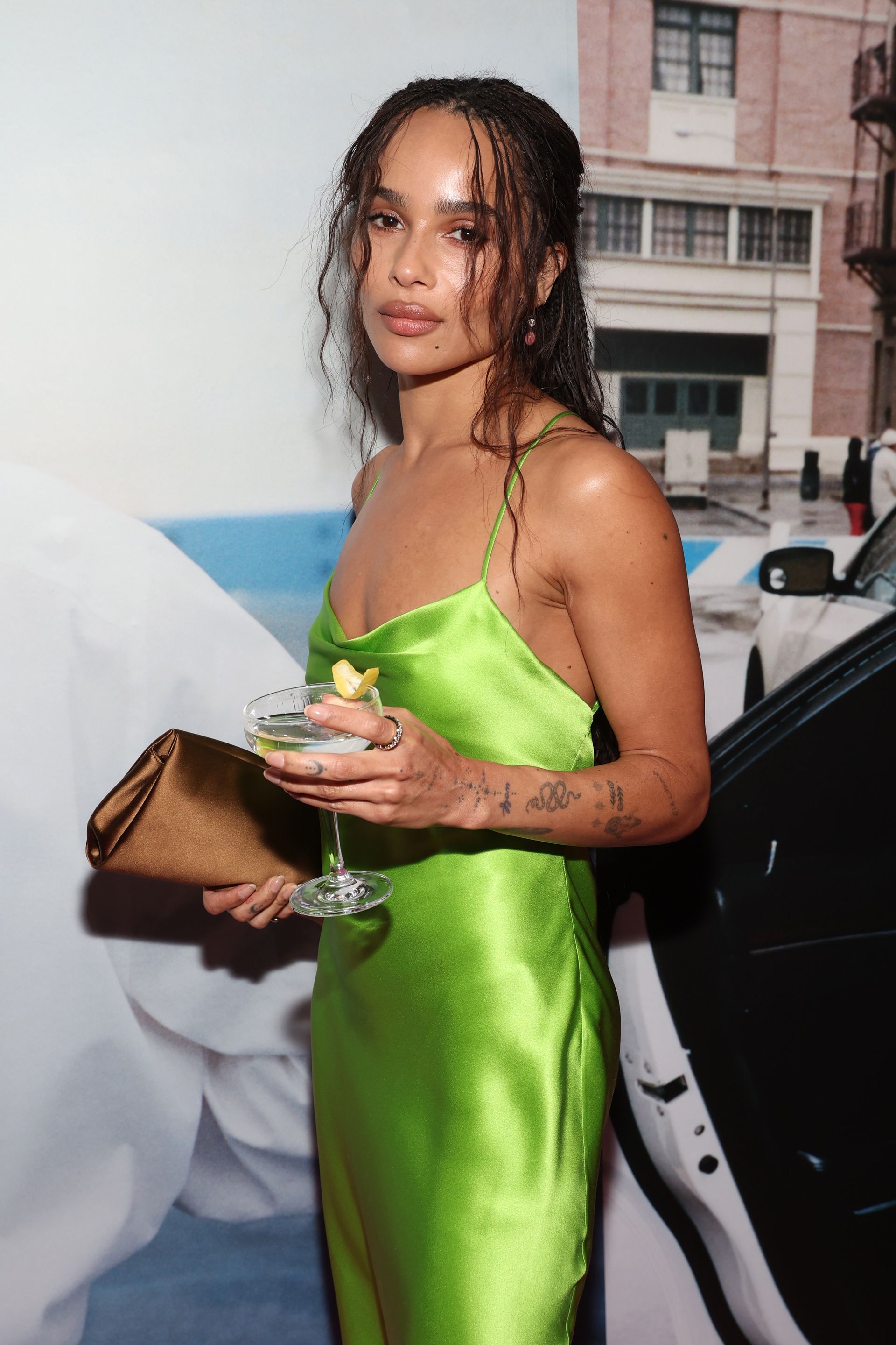 Zoe Kravitz wears a chartreuse satin dress with a brown satin bag.