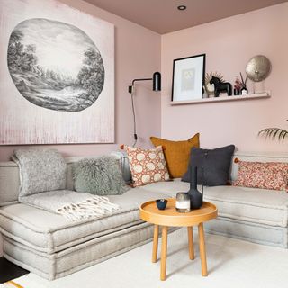 Pink living room with low cream sofa, wall shelving and large artwork