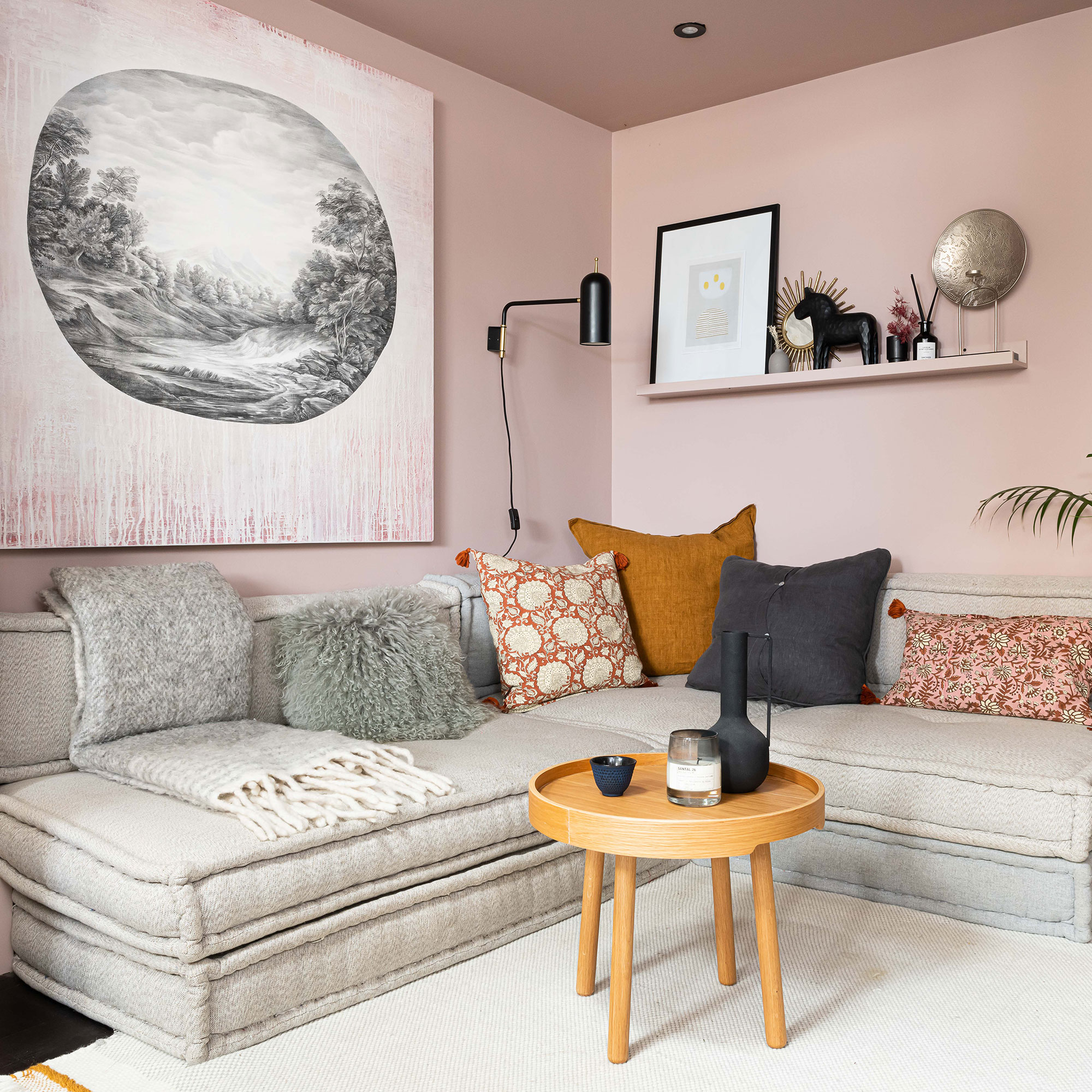 Pink living room with low cream sofa, wall shelving and large artwork