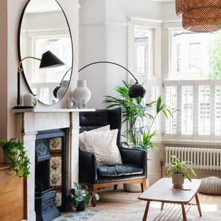 living room with bay window and cafe style shutters, next to armchair for reading and Victorian fireplace