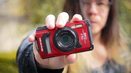 Photographer James Artaius holding up an OM System Tough TG-7 in an outdoor setting