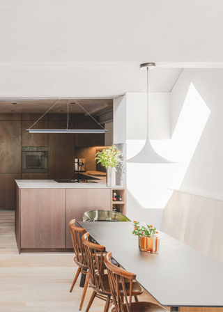 A light, open kitchen-dining space, with dark kitchen cabinets and white walls.