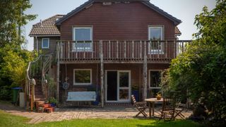 A timber framed house with balcony and outside stairs