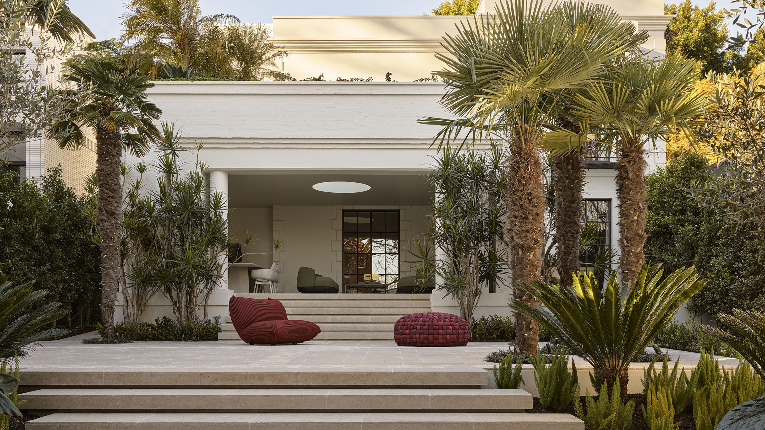 Exterior view of an Art Deco home in Woollahra, Sydney, renovated by Smac Studio, with lush subtropical landscaping, limestone terraces and collectible outdoor furniture.