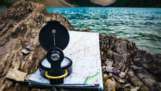 A map and compass by a lake