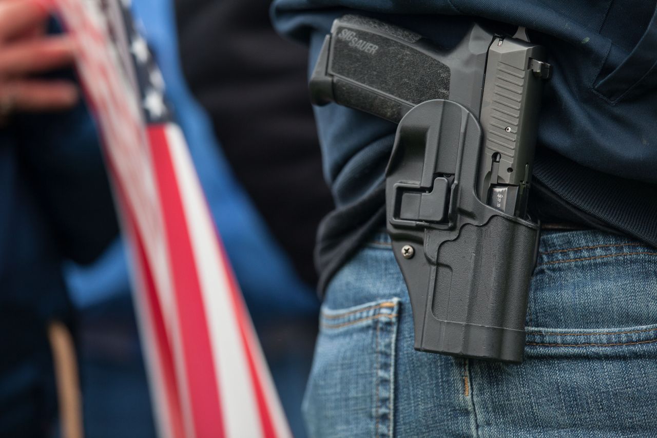 A man stands with a handgun at a rally.