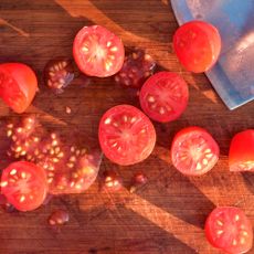 sliced tomatoes and seeds on chopping board with large silver blade