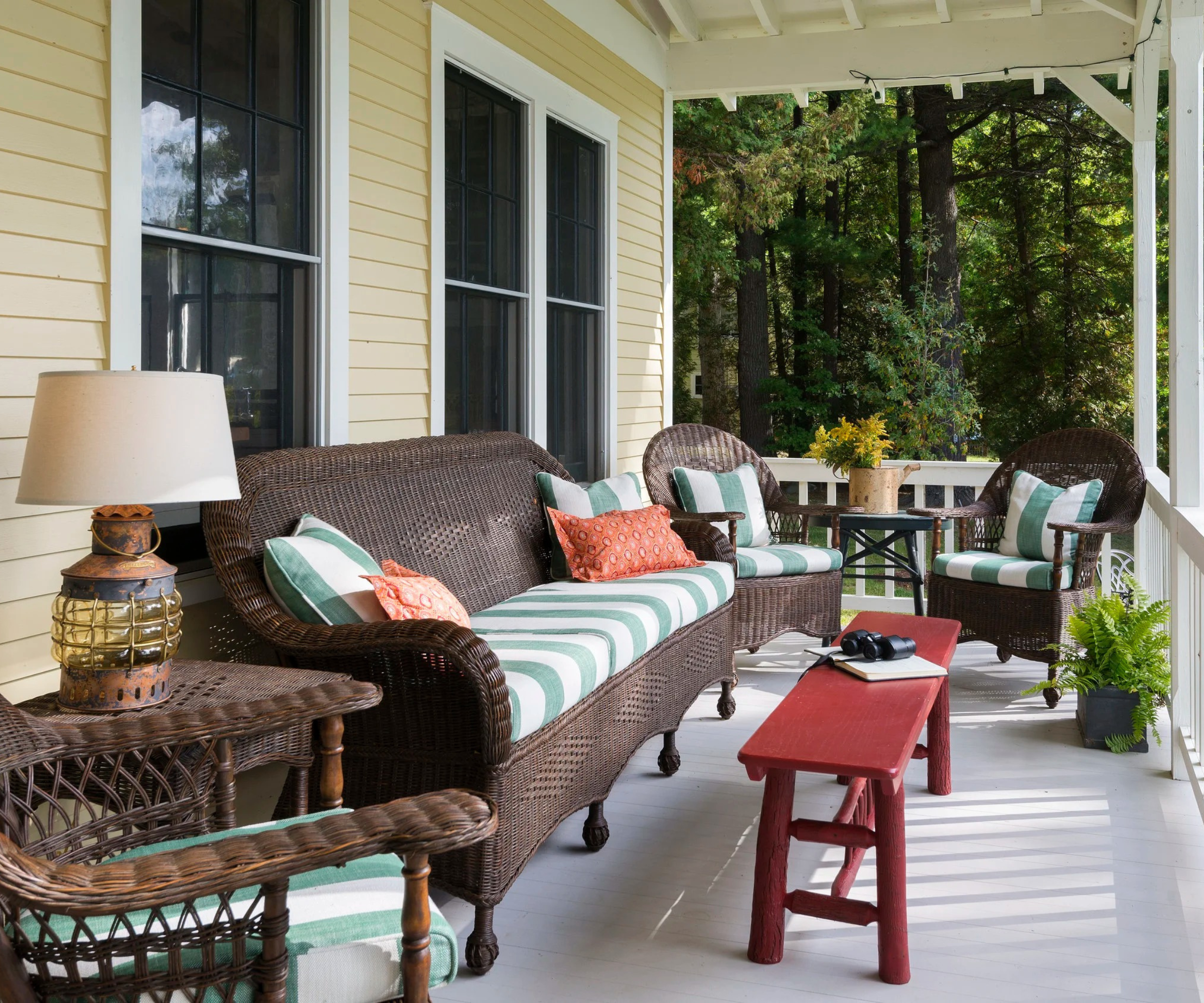 a porch with wicker outdoor furniture and a red bench