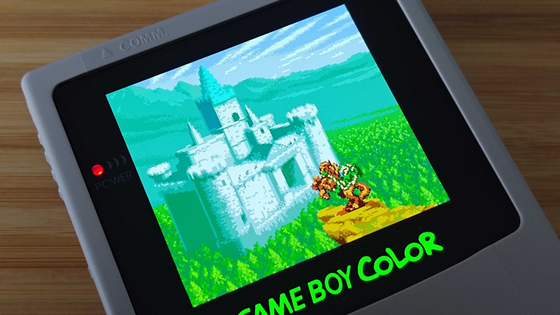 AMOLED screen modded Game Boy Color with closeup of Zelda: Oracle of Seasons intro with Link on horse in front of castle