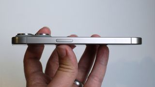En iPhone 15 Pro hålls upp av en hand och visas upp från sidan.
