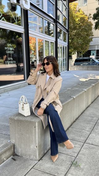 A former Nordstrom buyer wearing a tan trench coat with a white tee underneath.