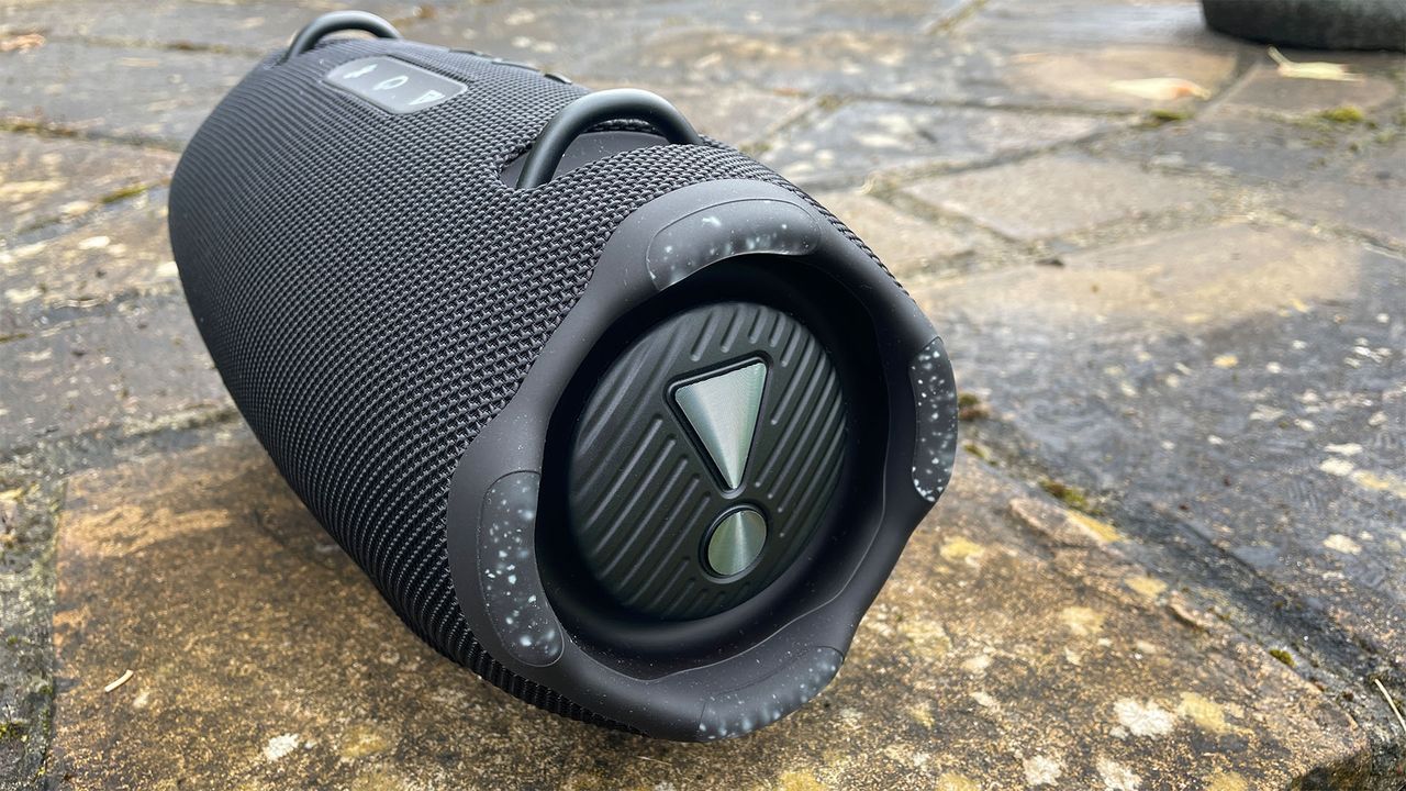 A black JBL Xtreme 4 wireless speaker on some paving slabs