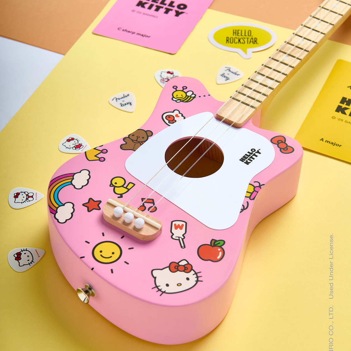 A Loog Hello Kitty Mini Acoustic guitar, sat on a yellow table