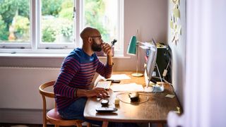 Home working tips to help you feel happy and healthy when remote working: a man sits at his home desk to work