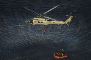 NASA Artemis II crew members are hoisted into a U.S. Navy MH-60 helicopter after successfully splashing down in the Pacific Ocean following their 10-day mission around the Moon.