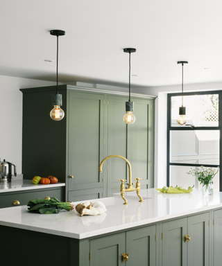 A dark green deVOL kitchen with bulb style kitchen lights design over an island.