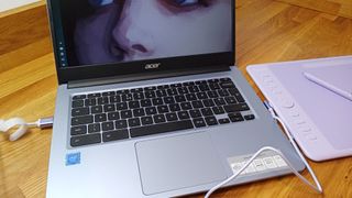 Acer 314, one of the best Chromebooks for students, placed on a wooden table with a drawing tablet