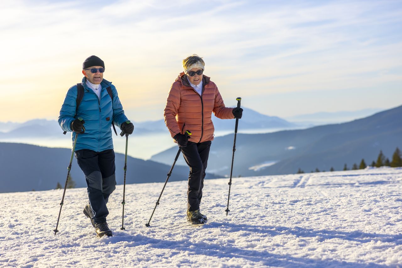 Older man and woman hiking on snowy mountain