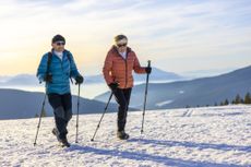 Older man and woman hiking on snowy mountain