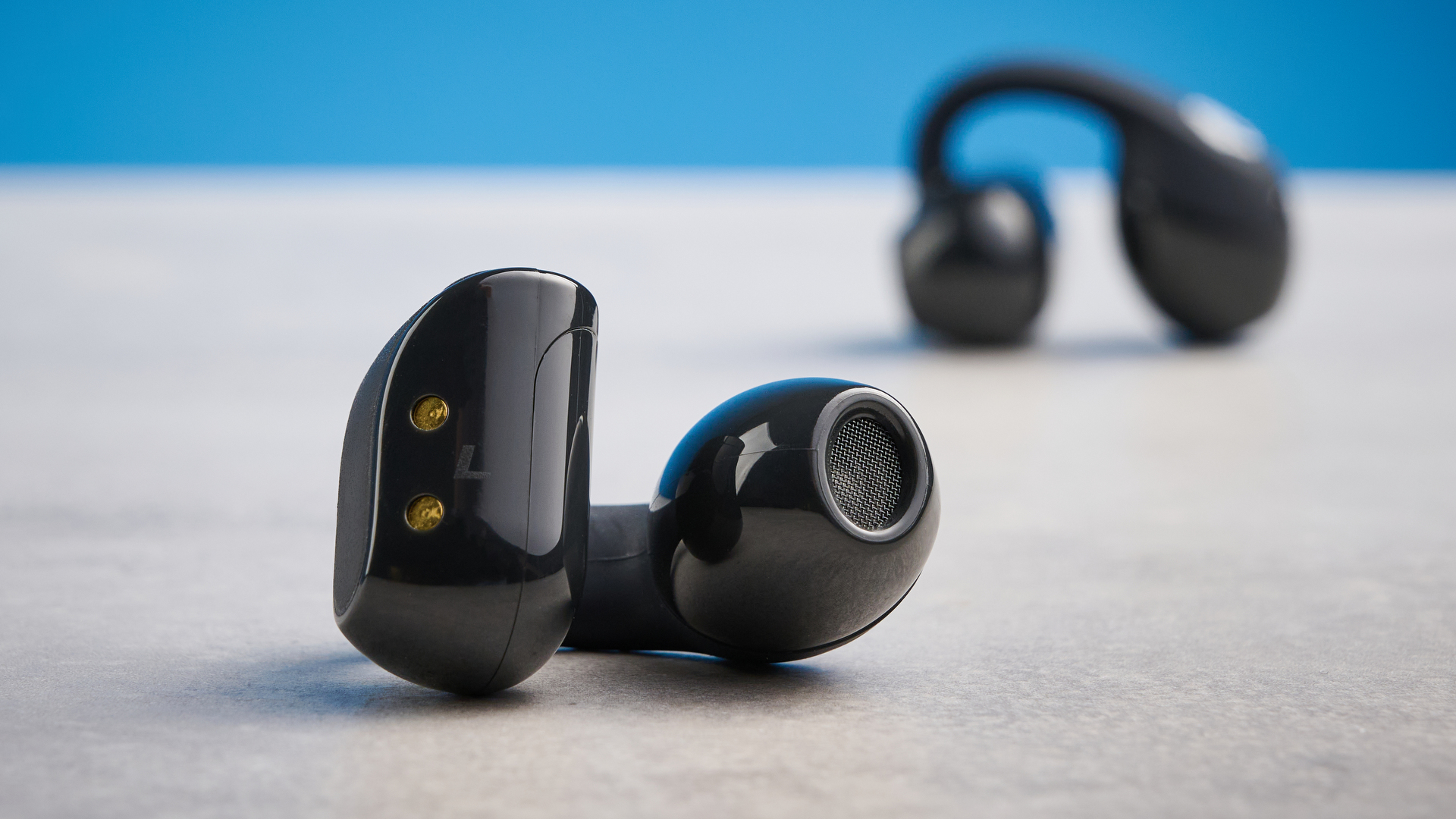 Skullcandy Push 720 Open in black and silver colorway with charging case photographed on a blue background