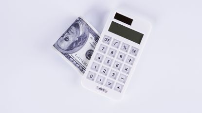 calculator next to folded dollar bills